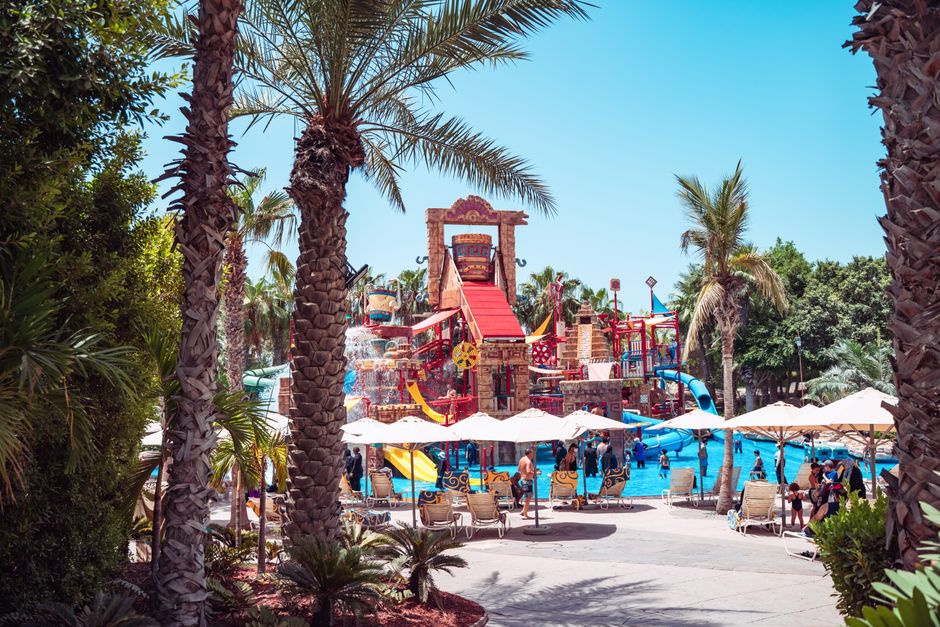 Área de lazer aquática com escorregadores, piscina e ambiente tropical, ideal para diversão em família e eventos ao ar livre.