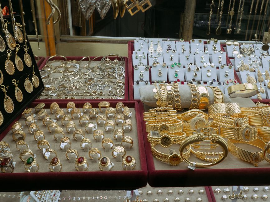 Vitrine com uma variedade de joias de ouro e prata exibidas à venda, destacando uma loja de acessórios de luxo.