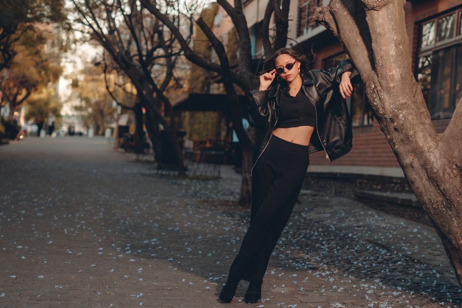 Mulher jovem posando com estilo urbano em passeio ao ar livre, refletindo moda e atitude contemporânea.