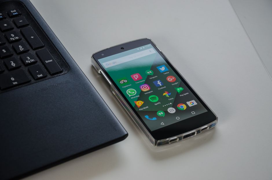 Imagem de um smartphone display com aplicativos de redes sociais ao lado de um computador, simbolizando conectividade digital e comunicação online.