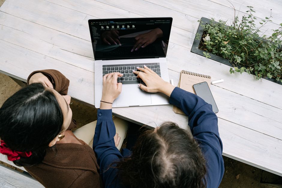 Dupla de profissionais colaborando em uma reunião de trabalho, usando um laptop para discutir estratégias empresariais.