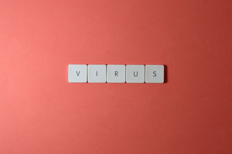 Imagem com blocos de letras formando a palavra 'VÍRUS' sobre fundo laranja, simbolizando a temática de saúde ou pandemia.