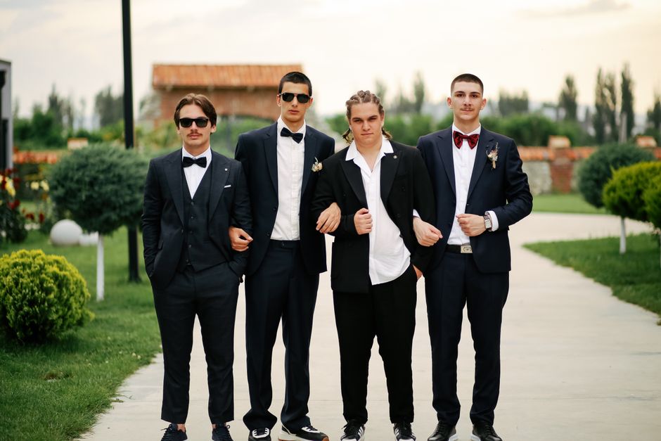 Grupo de jovens vestidos formalmente caminhando ao ar livre em um ambiente elegante, possivelmente para um evento especial ou celebração.