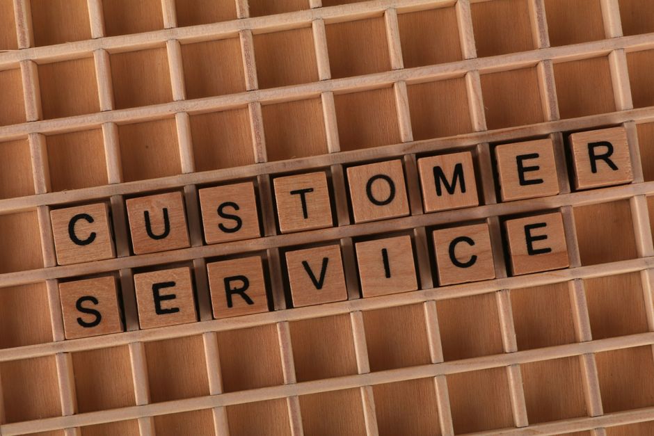 Imagem com blocos de madeira formando as palavras 'Customer Service', representando atendimento ao cliente.