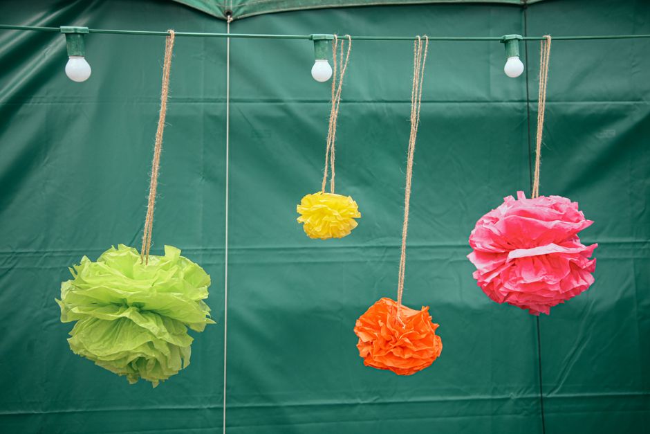 Decoração de festas com papel de seda colorido suspenso em um ambiente ao ar livre.
