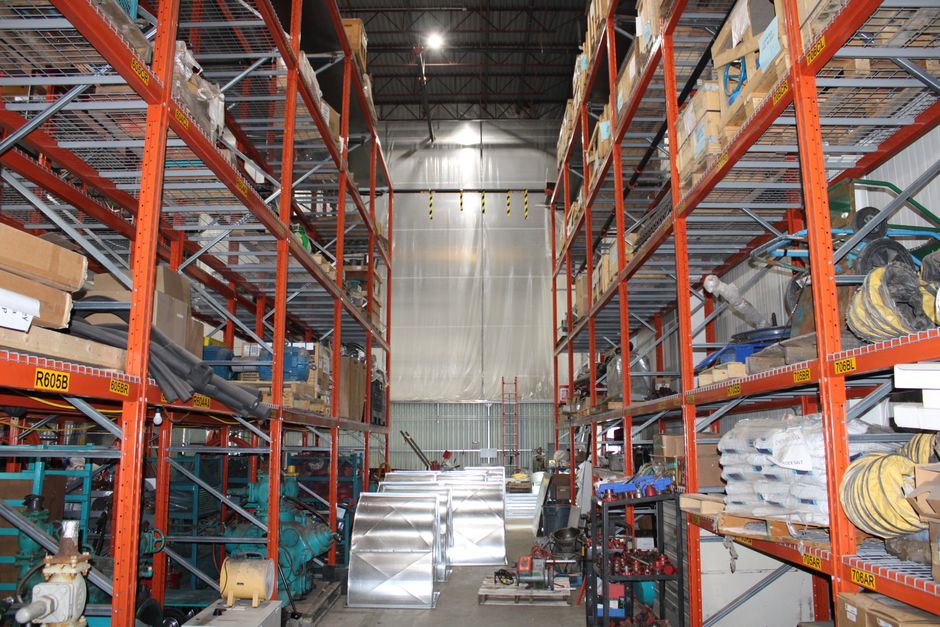 Imagem de um armazém industrial com estantes repletas de materiais e equipamentos para logística e armazenamento.