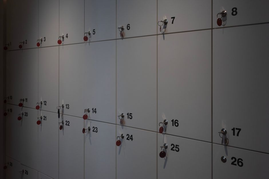 Imagem de um mural com compartimentos numerados e chaves penduradas, utilizado para organização e controle de objetos ou documentos.