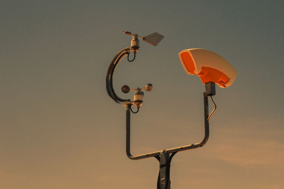 Imagem de um conjunto de instrumentos meteorológicos ao pôr do sol, simbolizando previsões e monitoramento do clima.