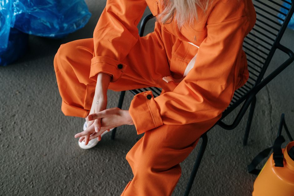 Imagem de uma pessoa vestida com uniforme laranja sentado em uma cadeira, indicando um cenário de trabalho ou atividade recente, possivelmente relacionado a trabalhos manuais ou operacionais.