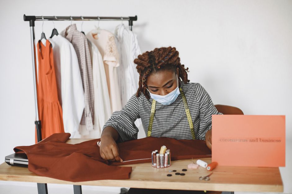 Costureira ajustando uma peça de roupa em um ateliê, com foco em moda e confecção.