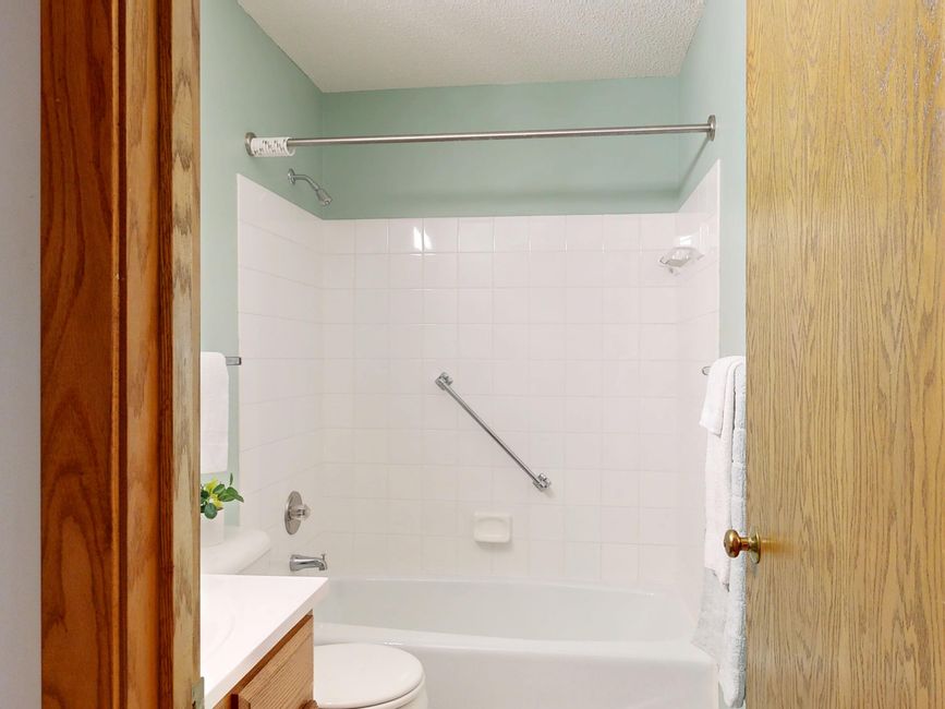 Imagem de um banheiro simples com banheira, parede de azulejos brancos e decoração minimalista.