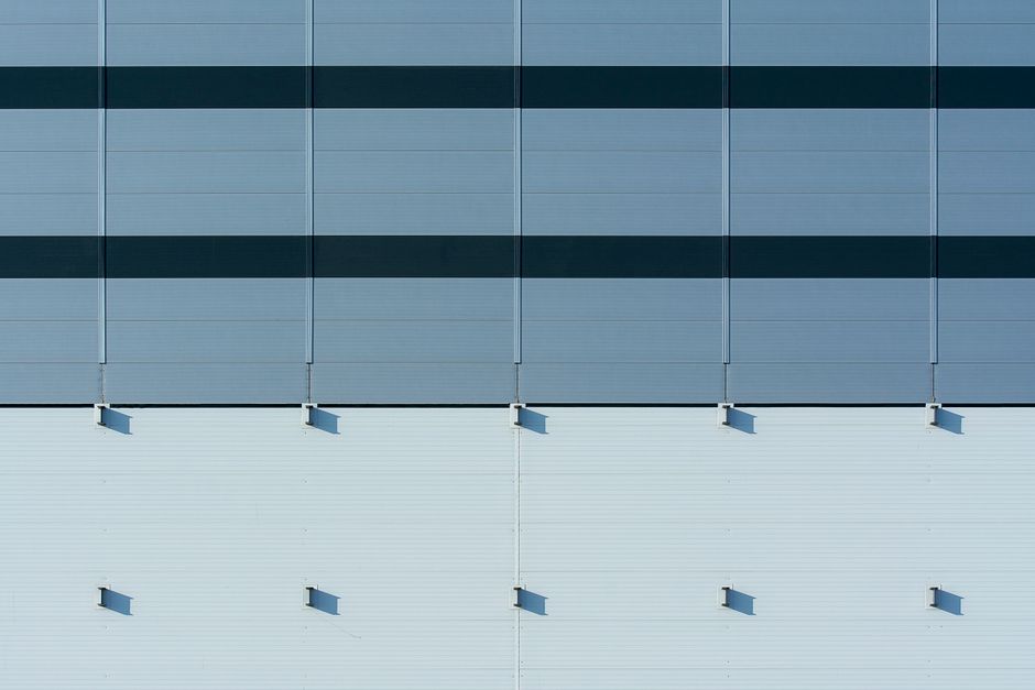 Imagem de uma fachada de edifício moderno com painéis de vidro refletindo o céu, simbolizando inovação e tecnologia corporativa.