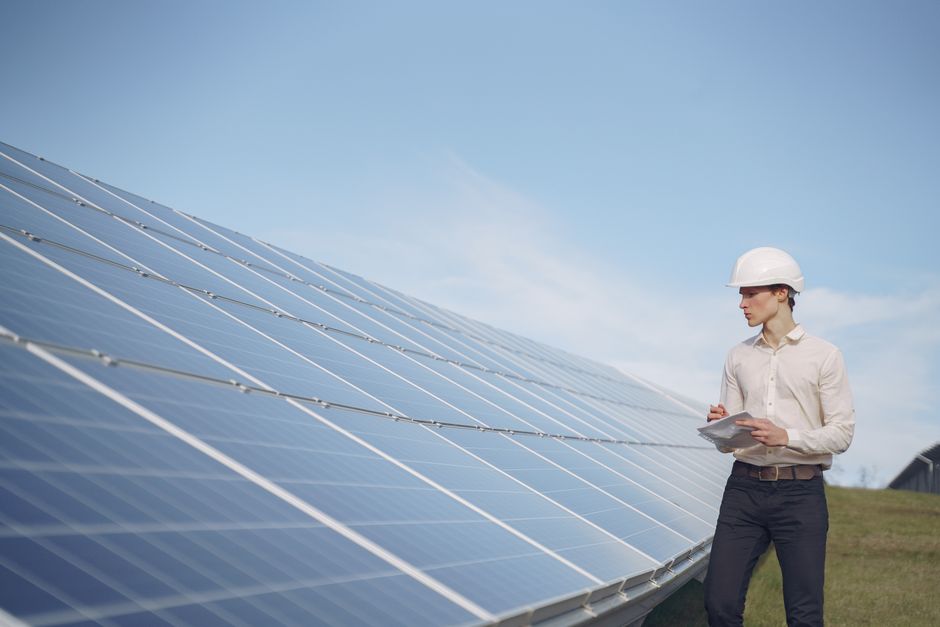 Profissional avaliando a instalação de painéis solares em um campo ao ar livre para artigos sobre energia renovável ou sustentabilidade.