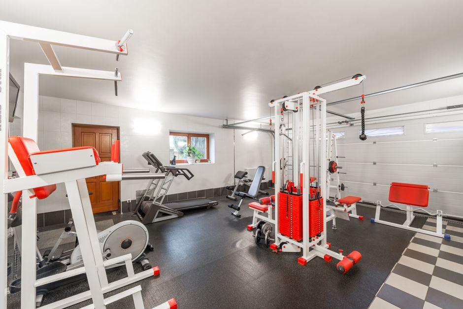 Imagem de uma academia doméstica organizada com equipamentos de musculação e cardio, ideal para ilustrar um espaço de exercícios físicos em casa.