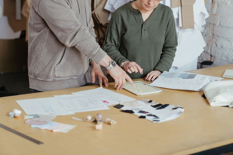 Equipe de profissionais analisando e discutindo projetos de moda ou design em um ambiente de trabalho criativo.