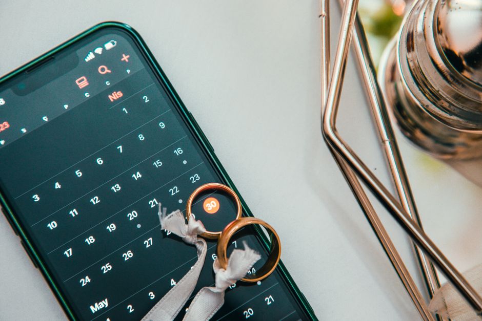 Imagem de um smartphone exibindo um calendário e dois anéis de casamento, simbolizando planejamento de casamento ou organização de datas especiais.