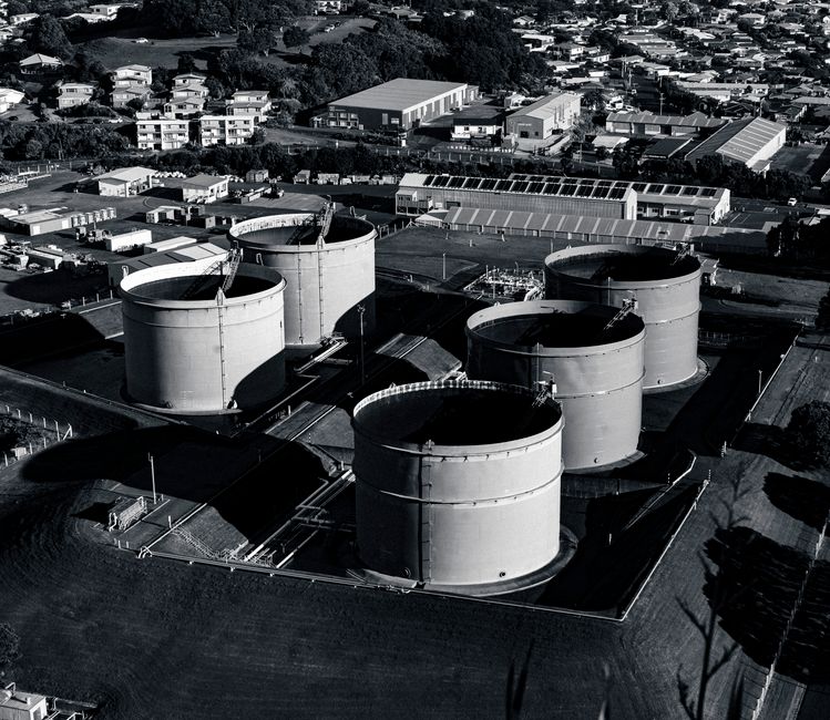 Imagem aérea de uma instalação industrial com tanques de armazenamento, destacando o setor de petroquímica ou petróleo.