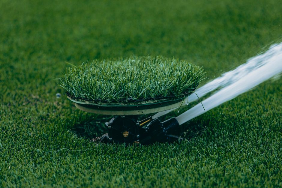Imagem de um atuador de grama artificial sendo utilizado para manutenção de um gramado bem cuidado.