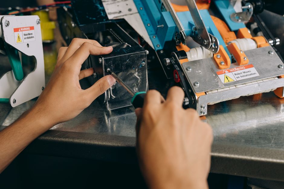 Pessoa ajustando componentes de uma máquina industrial em ambiente de produção tecnológica.