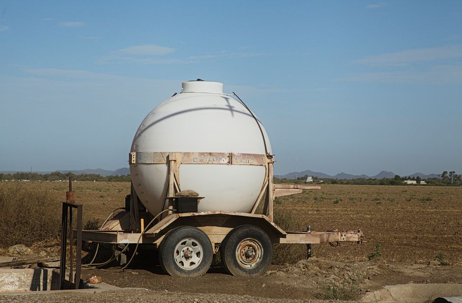 Imagem de um tanque de armazenamento de água em um campo aberto, com céu claro ao fundo, ideal para artigos sobre recursos hídricos ou sustentabilidade rural.