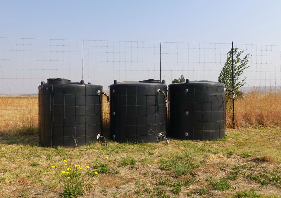 Imagem de tanques de armazenamento de água em ambiente rural ao ar livre, destacando a importância da irrigação e gestão de recursos hídricos na agricultura.
