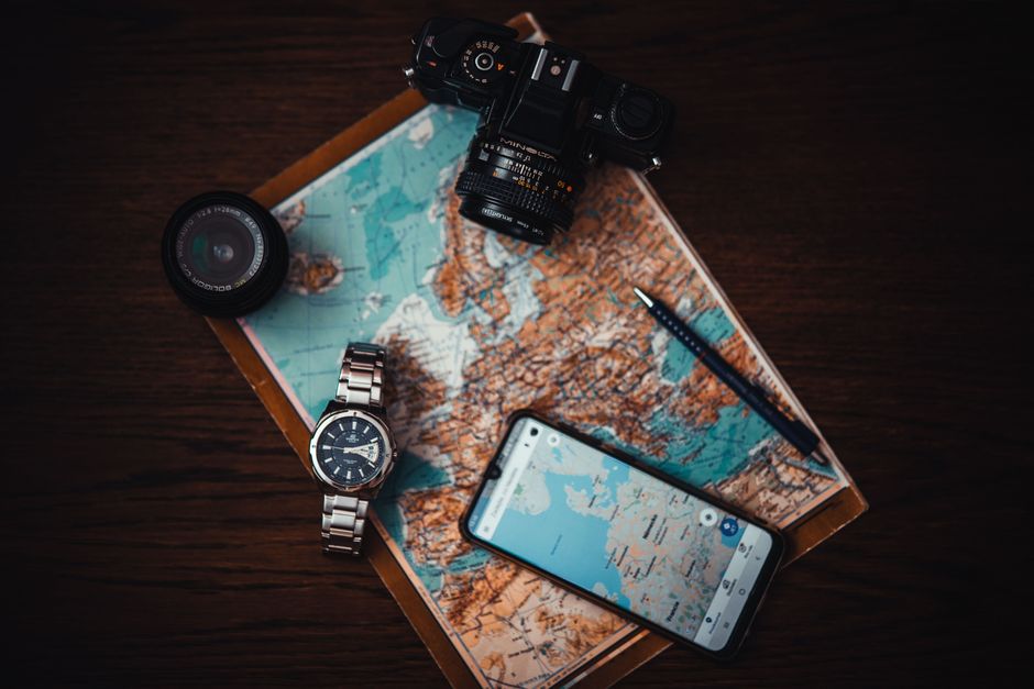 Imagem de um conjunto de itens de viagem e fotografia dispostos sobre um mapa, sugerindo planejamento de viagens ou exploração