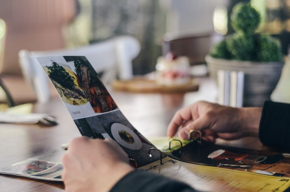 Pessoa revisando fotos ou projetos visuais em um ambiente de trabalho, com foco na análise de materiais impressos ou digitais.