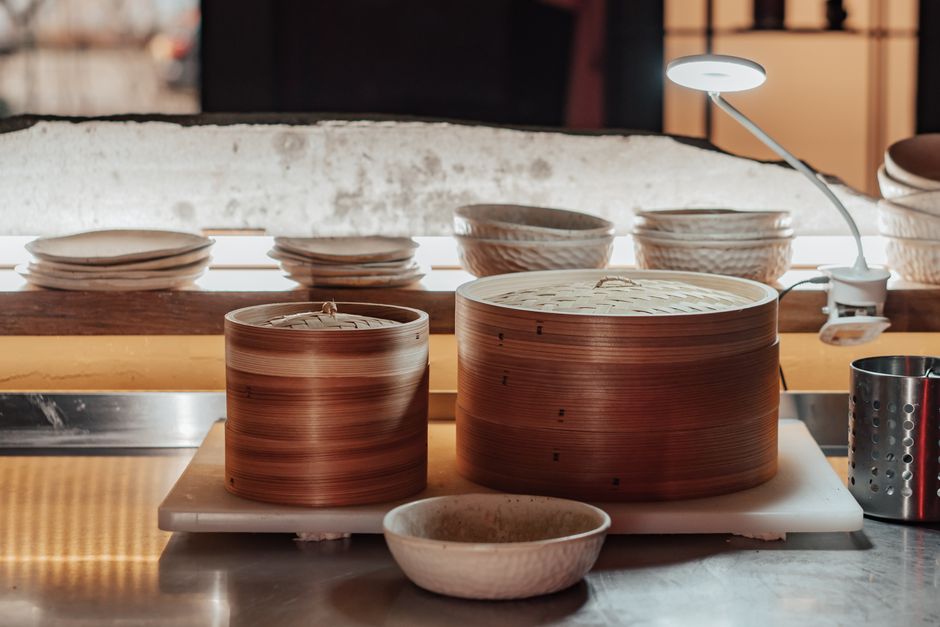 Conjunto de cestos de bambu usados na preparação de alimentos em uma cozinha tradicional japonesa, com foco na arte de fazer dim sum ou baos.