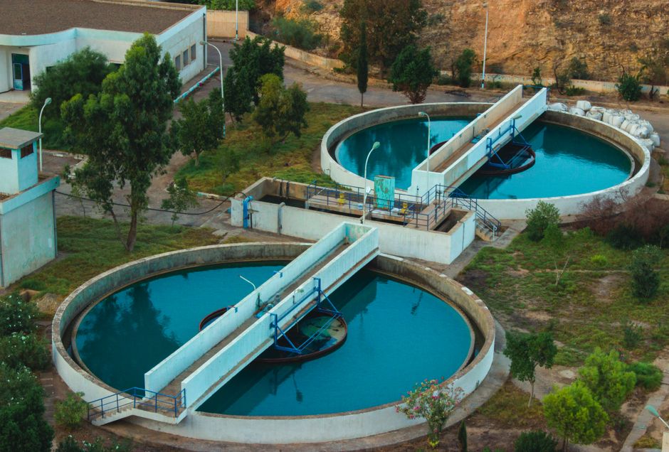Imagem de estações de tratamento de água ao ar livre, destacando a infraestrutura de saneamento básico em um ambiente natural.