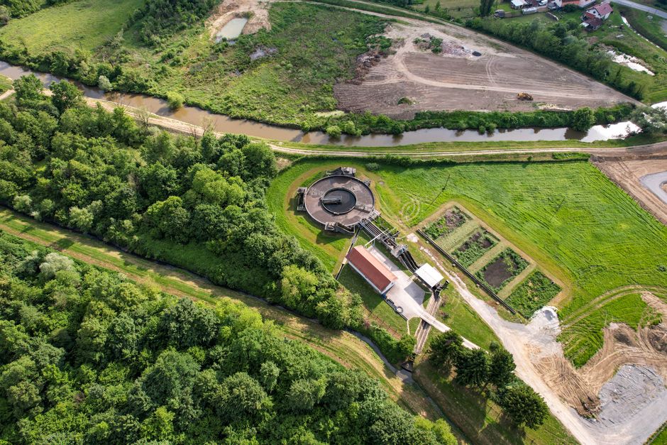 Imagem aérea de uma estação de tratamento de água em meio à vegetação, destacando a importância do saneamento básico.