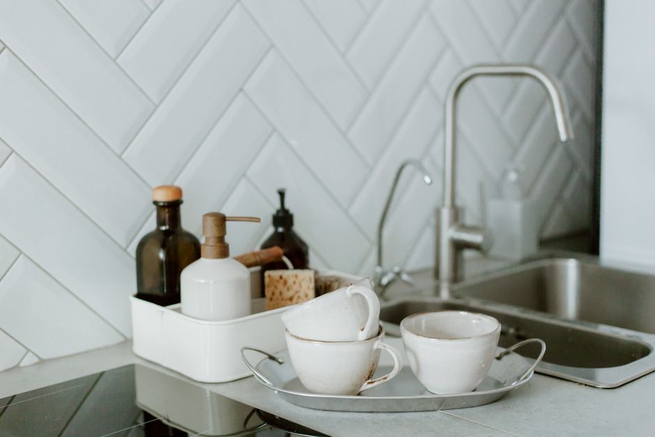 Imagem de uma cozinha moderna com utensílios de limpeza e louça, transmitindo conforto e organização no espaço doméstico.