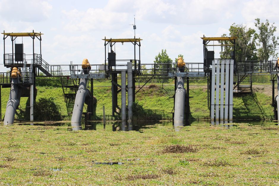 Imagem de uma estrutura de captação de água, com канис de aço e plataformas elevadas, situada em um ambiente natural ao ar livre, sob céu parcialmente nublado.