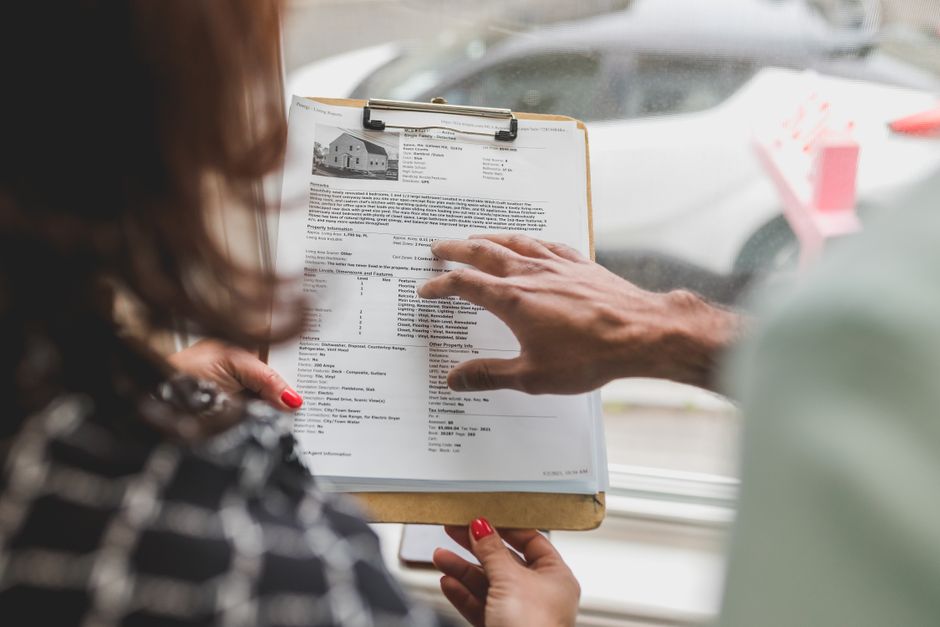 Pessoa analisando documento de avaliação de imóvel em ambiente de escritório, destacando o processo de revisão imobiliária.