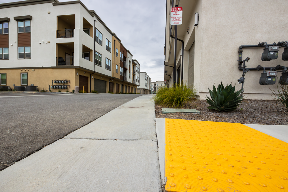 Imagem de uma rua residencial moderna com edifícios de apartamentos, destacando acessibilidade e urbanismo