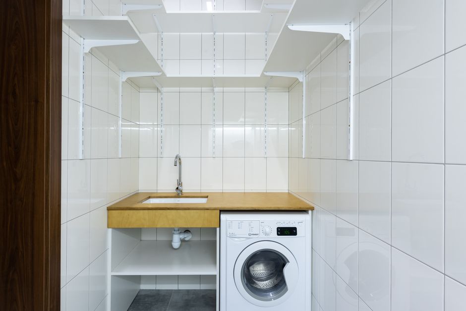 Imagem de uma lavanderia compacta com pia e máquina de lavar, ideal para artigos sobre otimização de espaços e organização doméstica.