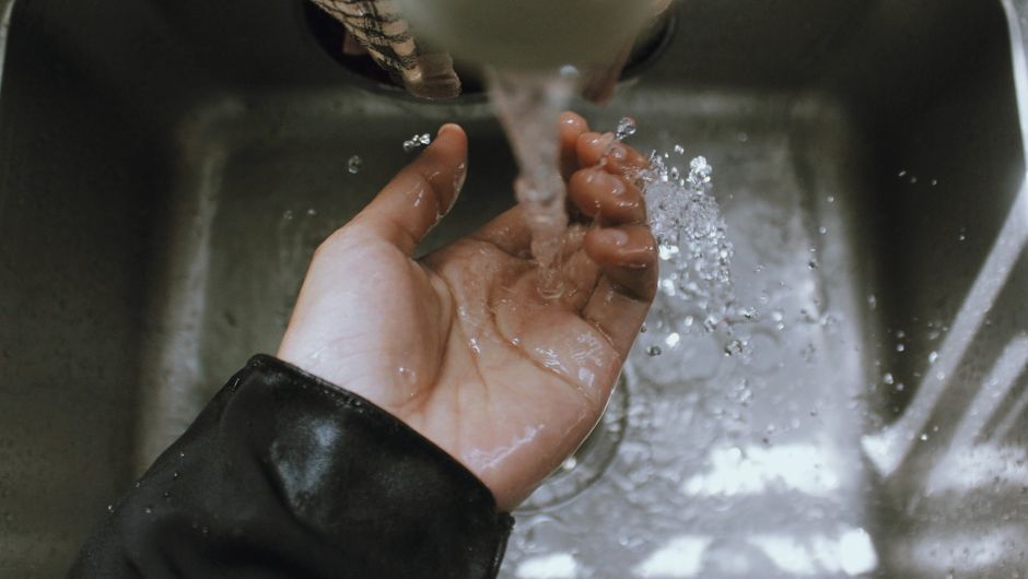 Pessoa lavando as mãos sob torneira com água corrente, evidenciando higiene e cuidados pessoais.