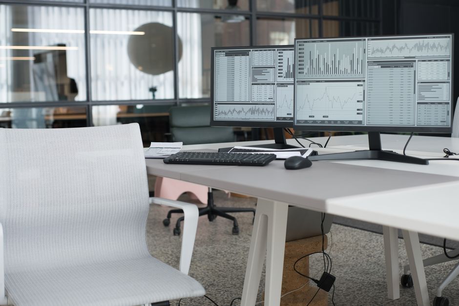 Ambiente de trabalho com múltiplos monitores exibindo dados financeiros e gráficos, ideal para artigos sobre análise de investimentos ou gestão de dados financeiros.