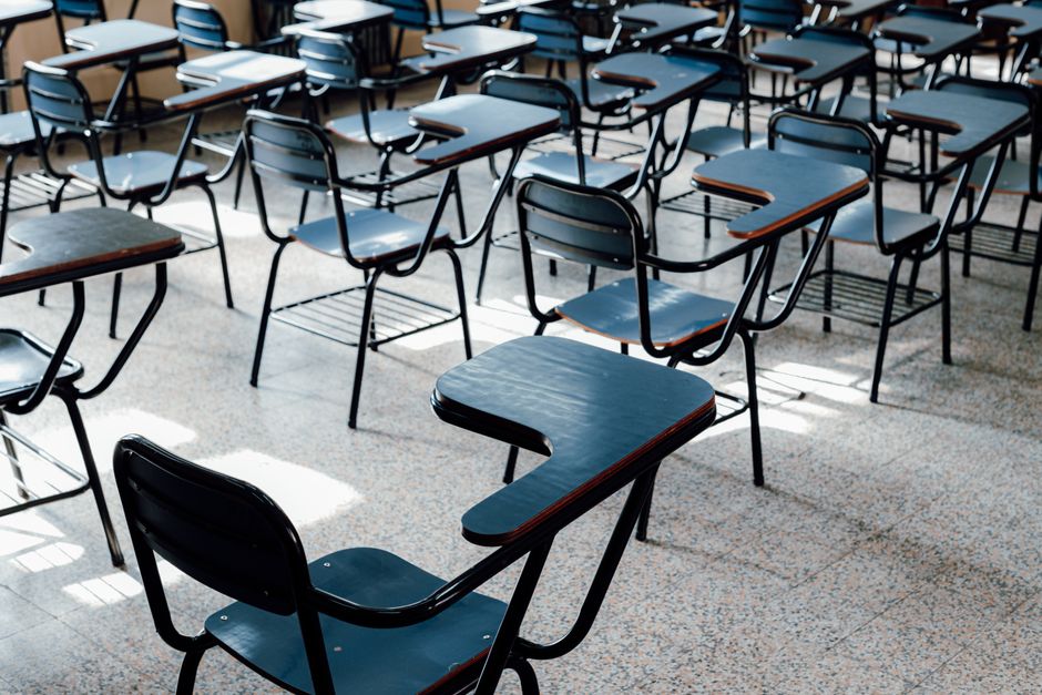 Salas de aula vazias com cadeiras de estudo organizadas em filas, sugerindo preparação para uma aula ou palestra.
