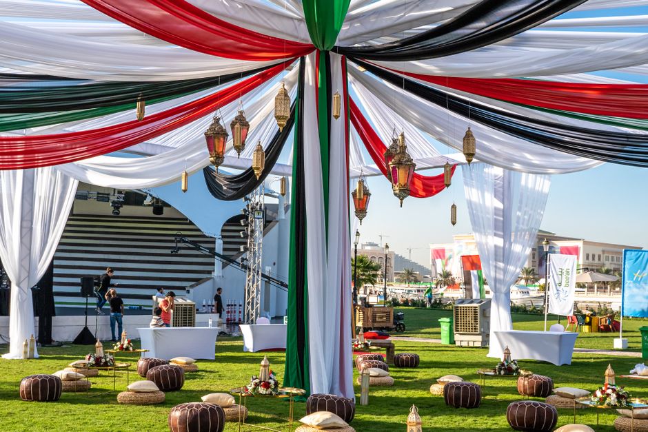 Preparativos para um evento ao ar livre decorado com tecidos coloridos e lanternas, em um espaço ao ar livre com ambiente festivo.