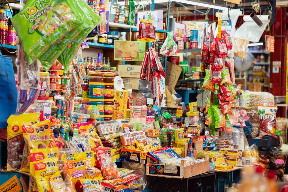 Imagem de uma banca de feira com diversas opções de doces e guloseimas coloridas, atraindo consumidores que buscam snacks e confeitos.