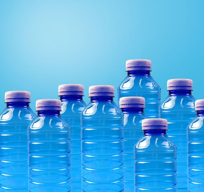 Imagem de várias garrafas de água mineral transparentes com tampas roxas, simbolizando pureza e hidratação.