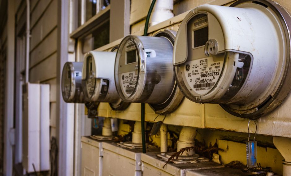 Imagem de medidores de energia elétrica instalados em uma parede, simbolizando o monitoramento e controle de consumo energético.