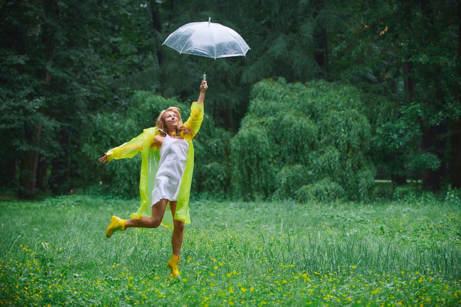 Mulher brincando com um guarda-chuva transparente em um cenário de floresta, transmitindo uma sensação de alegria e liberdade ao ar livre.