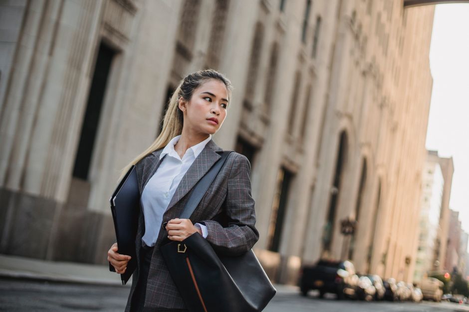 Mulher de negócios caminhando na cidade, simbolizando profissionalismo e público corporativo.