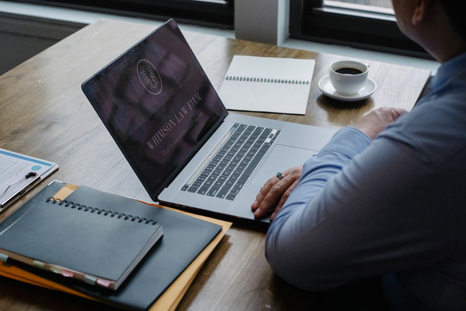 Pessoa trabalhando em um ambiente profissional com laptop, caderno e uma xícara de café, ideal para artigos sobre produtividade ou rotina de trabalho.
