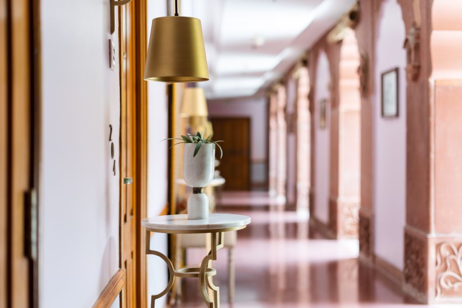 Corredor de um prédio elegante com iluminação sofisticada e decoração clássica, ideal para artigos sobre arquitetura e design de interiores.