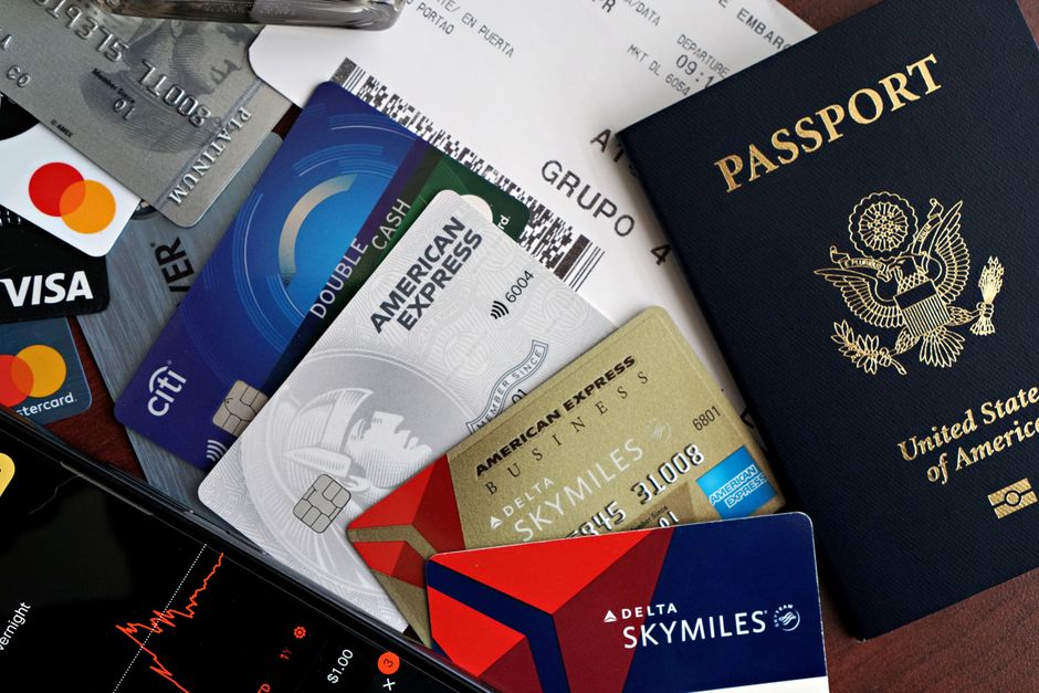 Imagem que mostra documentos, cartões de crédito, passaporte e um smartphone, simbolizando viagens internacionais e procedimentos de troca de moeda.