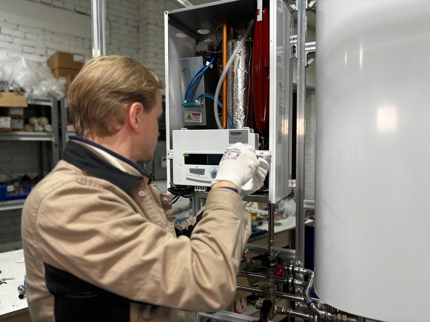 Técnico realizando manutenção em sistema de aquecimento ou aquecimento de água em configuração industrial ou residencial.
