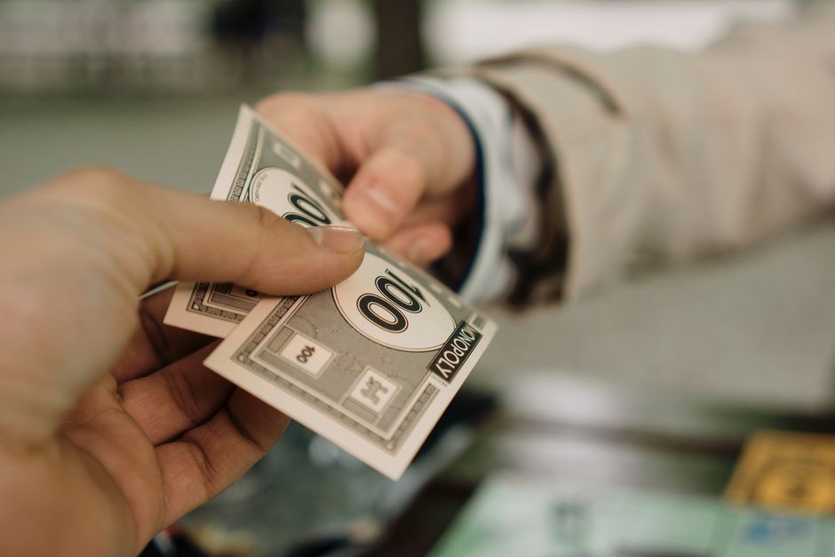 Pessoa trocando dinheiro em uma transação financeira, simbolizando negociação ou pagamento.