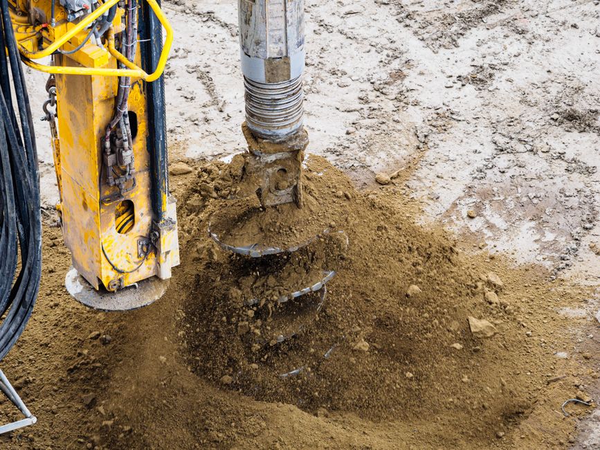 Imagem de uma broca de perfuração em solo, usada em obras de construção civil para escavar ou instalar fundações.